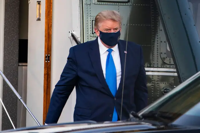 Trump wears a mask as he walks away from the helicopter